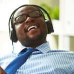 Image of young businessman taking pleasure in listening to his favourite music in office