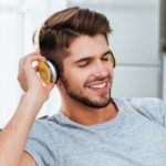 Man in headphones listening to lessons while lies on sofa